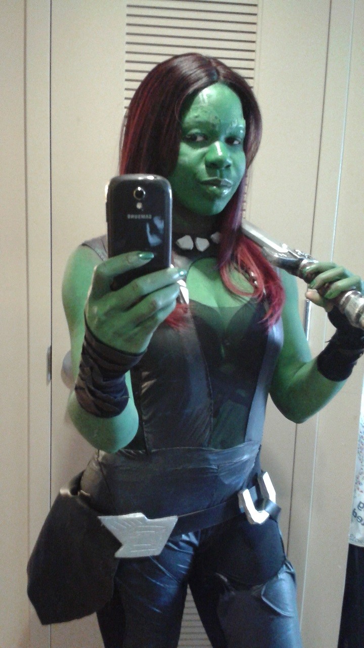 Jay Justice dressed as Gamora from Guardians of the Galaxy holding a sword over her shoulder as she takes a selfie